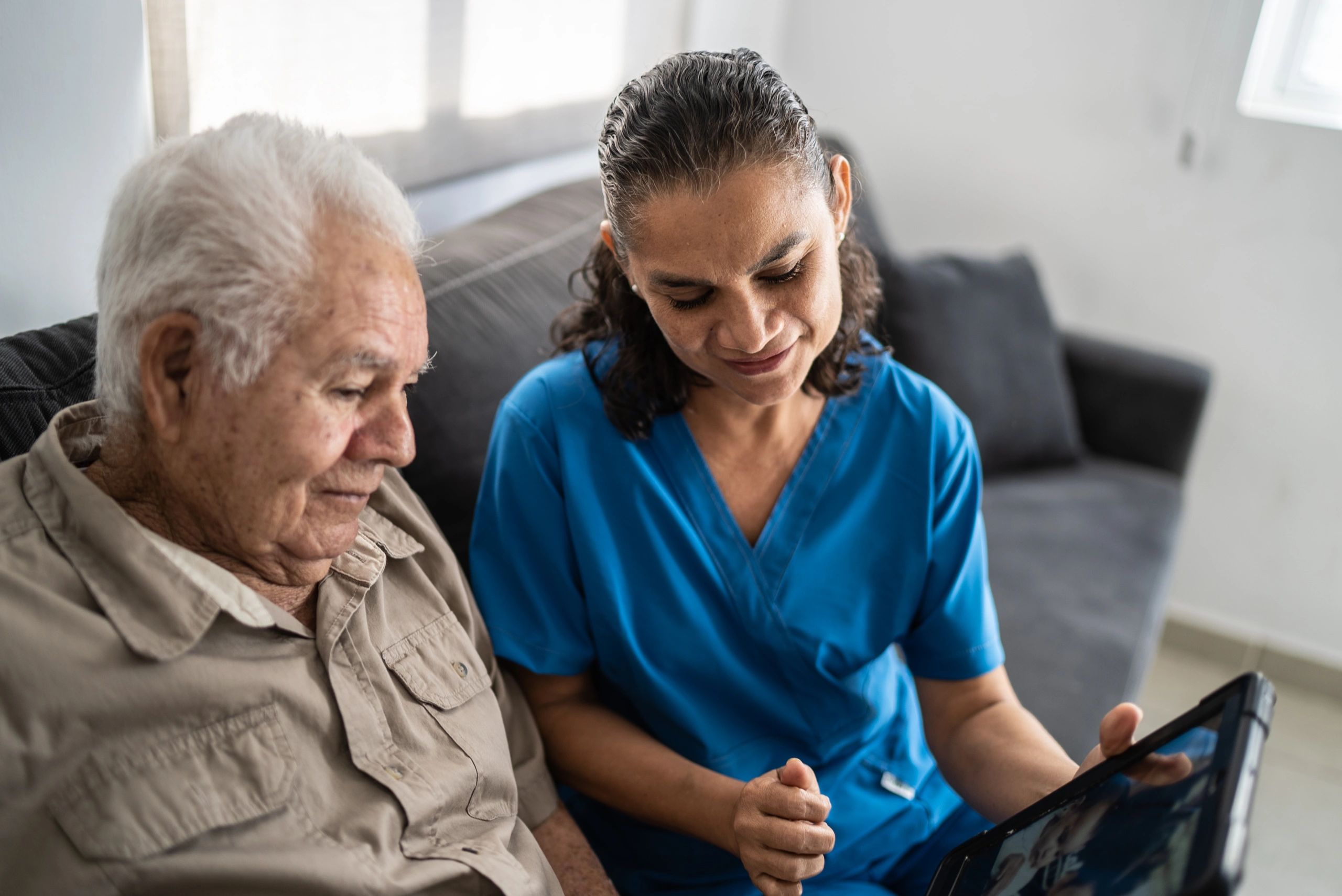 Caregiver helping a senior use a tablet at home