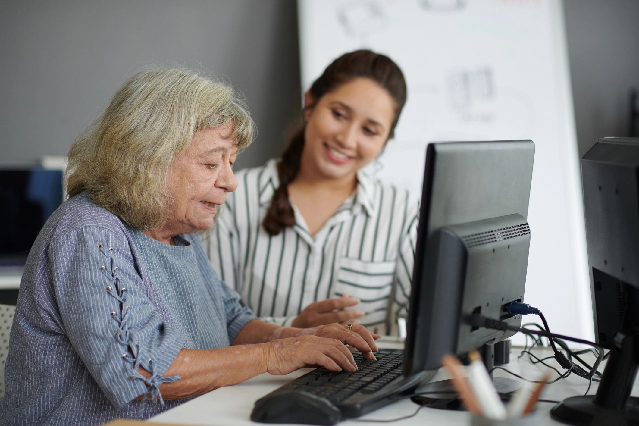 Senior using a computer with help from a professional